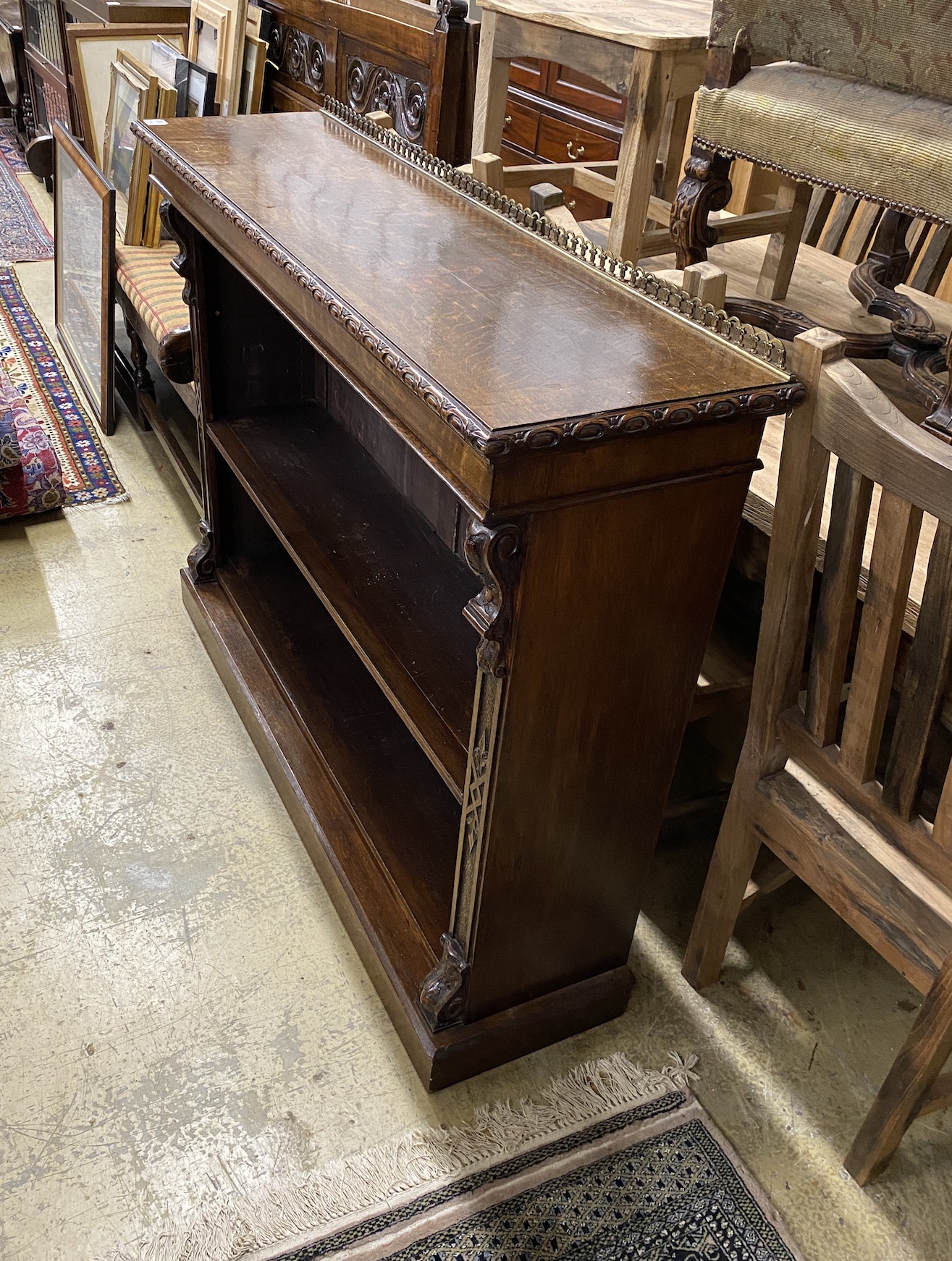 A late Victorian carved oak open bookcase, width 137cm, depth 37cm, height 108cm